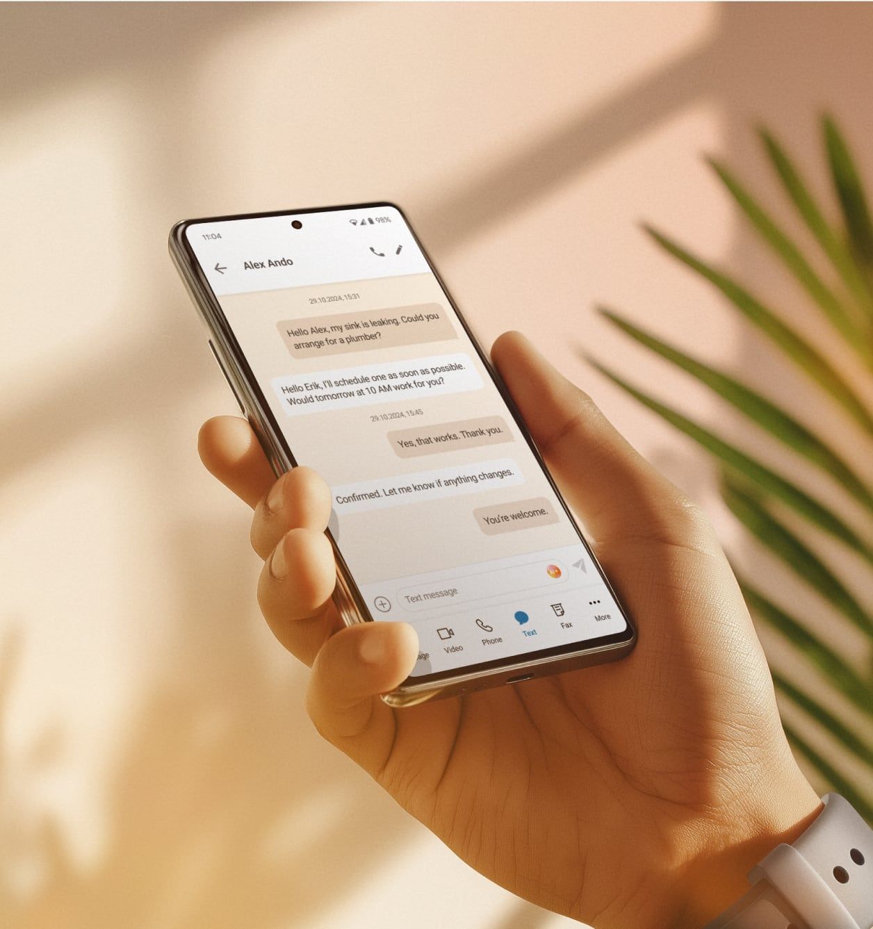 Hand holding a smartphone displaying business SMS messaging on the RingCentral mobile app to arrange client services.