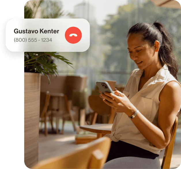 A lady sitting on a wood chair receives a call from Gustavo Kenter